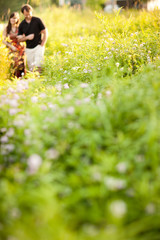 Young Woman and Man Walking Together in Meadow Outside