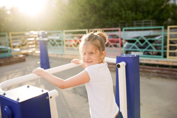 Funny child on fitness equipment in playground
