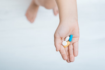 child hand with colorful pills on white background top view. Vitamins for children