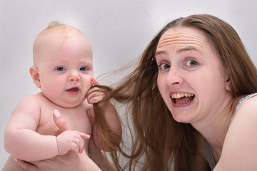 Mom and child are having fun together. Mother playing with cute baby in bed.