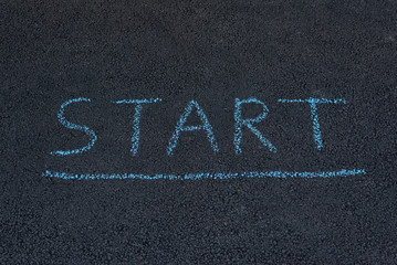Text START underfoot. Texture road surface. Black asphalt with chalk inscription.