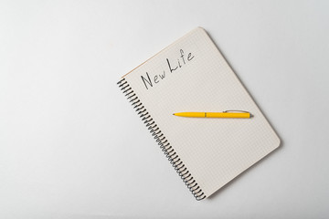 New Life motivation text on copybook. Notepad and pen on white background.