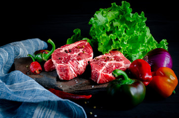 Meat concept. Meat steaks are ready to cook with vegetables lying on the table