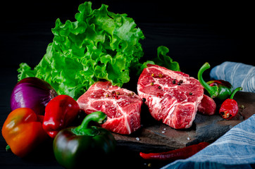 Meat concept. Meat steaks are ready to cook with vegetables lying on the table