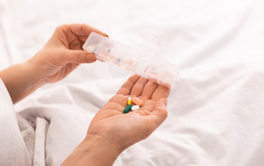 Close up of senior female hands taking pills from container