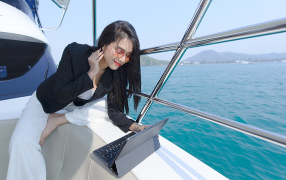 Beautiful Business Woman Working With Laptop On A Boat, A Young Woman Smile On The Yacht In Ocean, Office Worker In Yacht