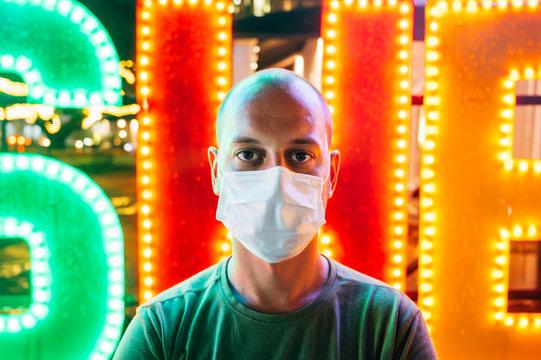 Portrait of man wearing mask standing in front of colorful lights