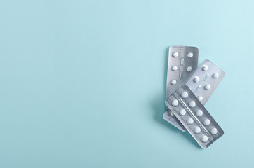 Top view of silver blister packs full of drugs on the light blue background.Empty space for text
