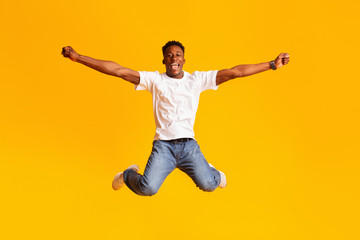 Fototapeta na wymiar Happy excited african man jumping in air, dancing