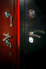 Steel doors of red and black colors with locks and keys close-up