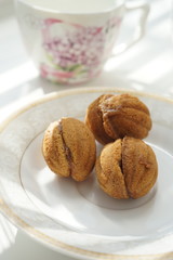 Cookies walnuts on a white saucer. Background pink tea cup on a sunny table
