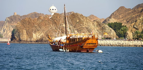 Hölzerne Dhau vor der Küste von Mutrah mit Bergen und Weihrauchbrenner im Hintergrund