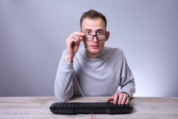 Funny nerd young businessman, man working on computer.Typing on the keyboard programmer in glasses...