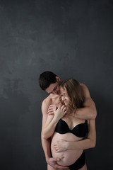 Obraz premium Happy man embracing his pregnant girlfriend and looking at camera.