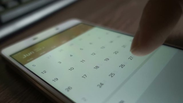  Man using calendar app on the mobile device closeup. Close-up male hands scrolling screen on smartphone.