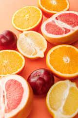 Fototapeta na wymiar Selective focus of citrus fruits halves and apples on orange background