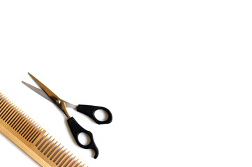 Wooden comb and scissors for a haircut isolated on a white background.