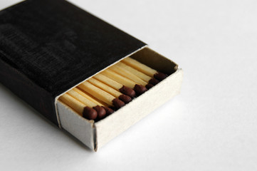 Wooden safety matchsticks stacked in cardboard matchbox.