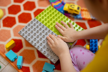 Multi-colored plastic constructor in the hands of the girl. Children's educational games.