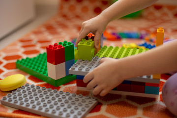 Multi-colored plastic constructor in the hands of the girl. Children's educational games.