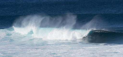 Dramatic white surf and spray as turquoise blue ocean waves roll