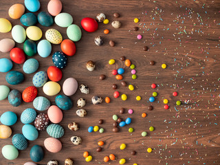 Fototapeta na wymiar Colorful Easter eggs on wooden table with candies. Easter holiday decorations , Easter concept background.