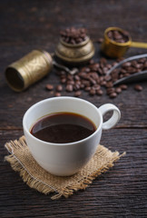 Hot coffee cup with premium arabica coffee beans on the wooden table.