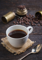 Hot coffee cup with premium arabica coffee beans on the wooden table.
