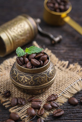 Ground coffee and a vintage brass grinder on wooden table.copy space