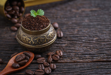 Ground coffee and a vintage brass grinder on wooden table.copy space