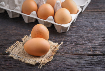 Raw eggs in egg box on rustic wooden background.