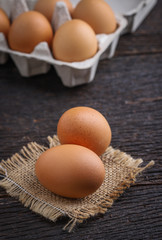 Raw eggs in egg box on rustic wooden background.