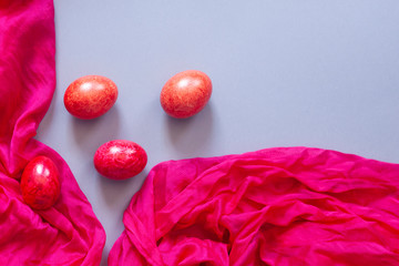 Colorful Easter eggs and silk textile material. Festive Easter holiday concept. View from above. Copy space. Top view