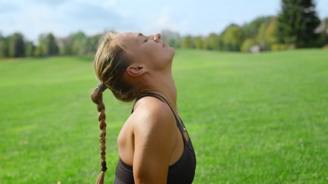 Sportswoman with artificial limb doing yoga in park. Woman stretching in field