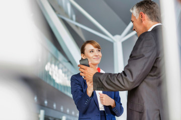 Businessman showing his electronic ticket on smartphone to passenger service agent in airport