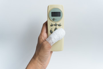 thumb was wrapped in a white bandage due to an accident touch white remote control air condition on white background