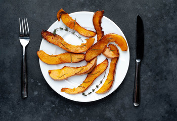 slices of fried pumpkin on a white plate on a stone background