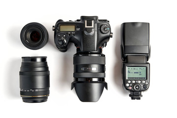 top view of modern digital camera equipment - DSLR with attached zoom lens and hood, lenses and...