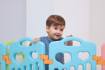 Cute little child playing in modern playpen at home