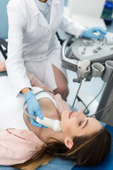 Fototapeta premium doctor examining thyroid of female patient with ultrasound scan in clinic