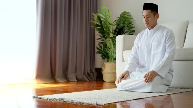 Portrait of Asian Muslim man reciting surah al-Fatiha passage of the Qur'an, in a daily prayer at home in a single act of sujud called a sajdah or prostration