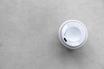 paper cup and hot coffee on cement floor background. top view