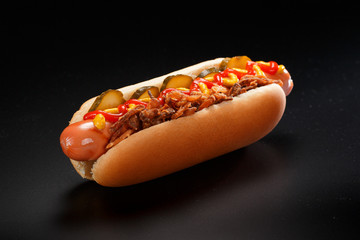 Danish hot dog with pickled cucumbers, fried onions and a hot dog with mustard, lettuce and jalapenos on a black background. - obrazy, fototapety, plakaty