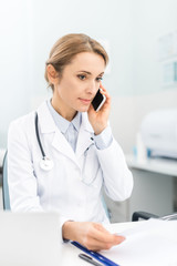 professional doctor holding talking on smartphone in clinic