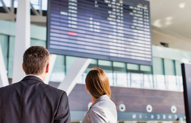 Business people looking on flight display screen in airport