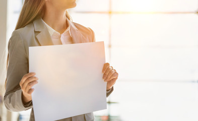 Portrait of businesswoman standing while holding blank white board in arrival area at airport