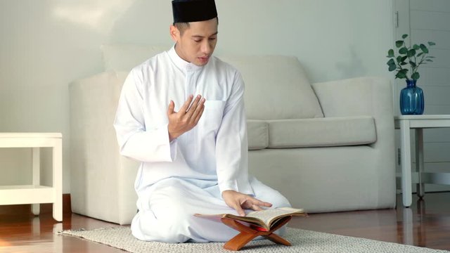 Portrait of Asian Muslim man reciting surah al-Fatiha passage of the Qur'an, in a daily prayer at home in a single act of sujud called a sajdah or prostration