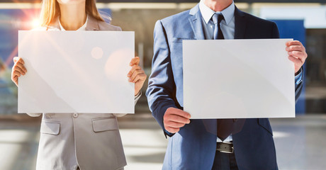 Business people standing while holding blank white placard in arrival area at airport