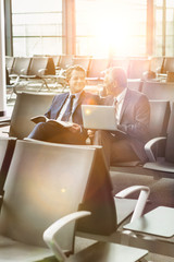 Portrait of business people sitting while waiting for boarding in airport