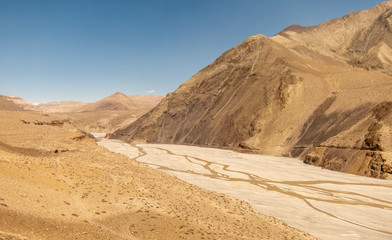 The wide river bed of the Kali Gandaki river winding through the arid canyons of the cold desert in...